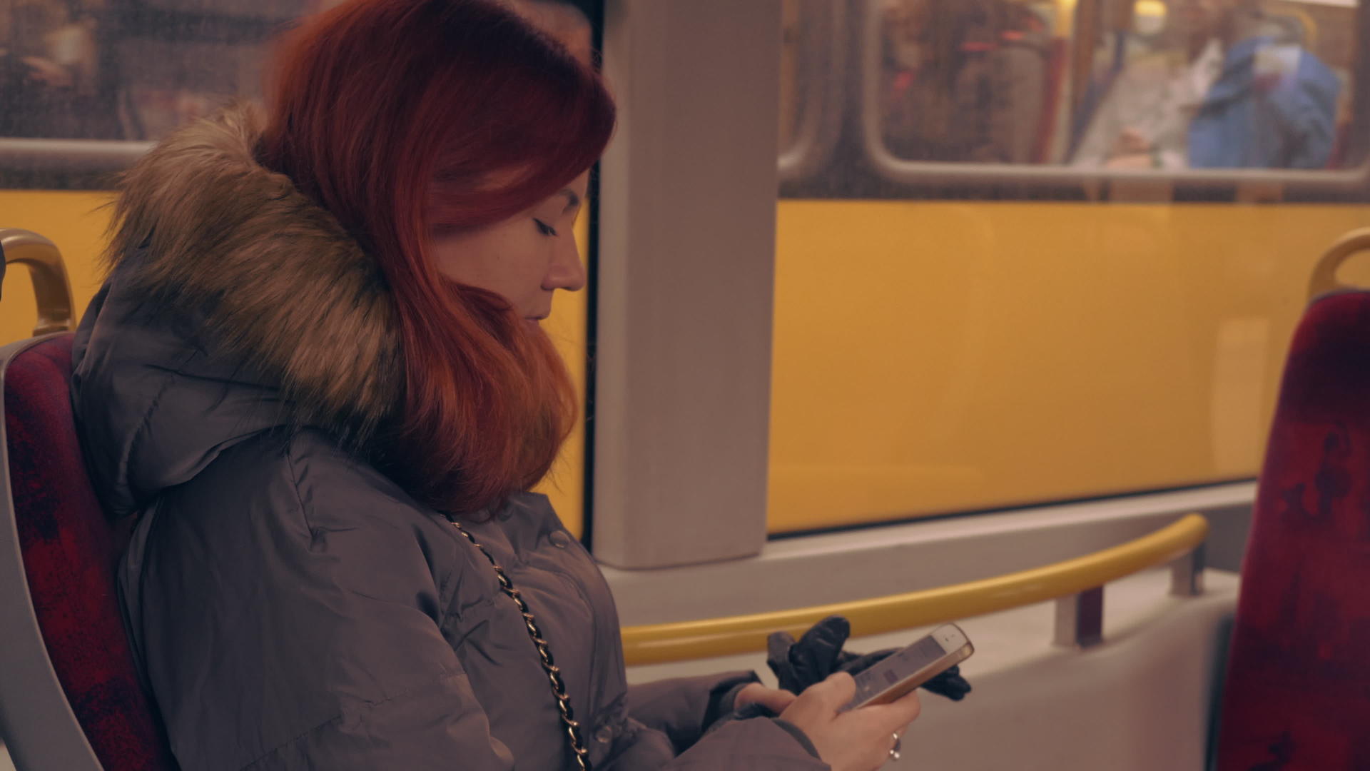 坐在电车上的红发女性使用智能手机上网视频的预览图