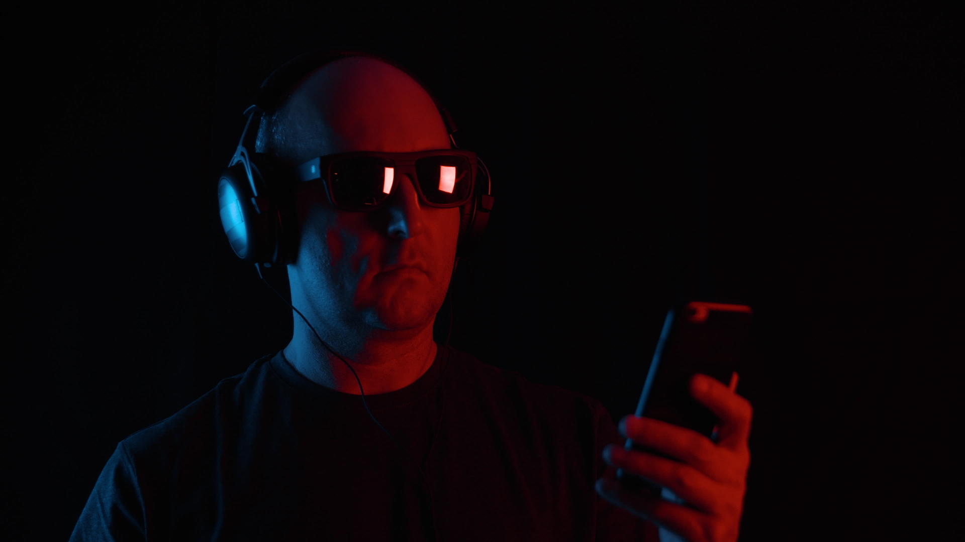 在黑暗中使用智能手机耳机和太阳镜的人视频的预览图