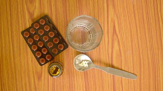 勺子瓶的顶部视图一杯水中的药丸或药片以及木桌的背景视频的预览图
