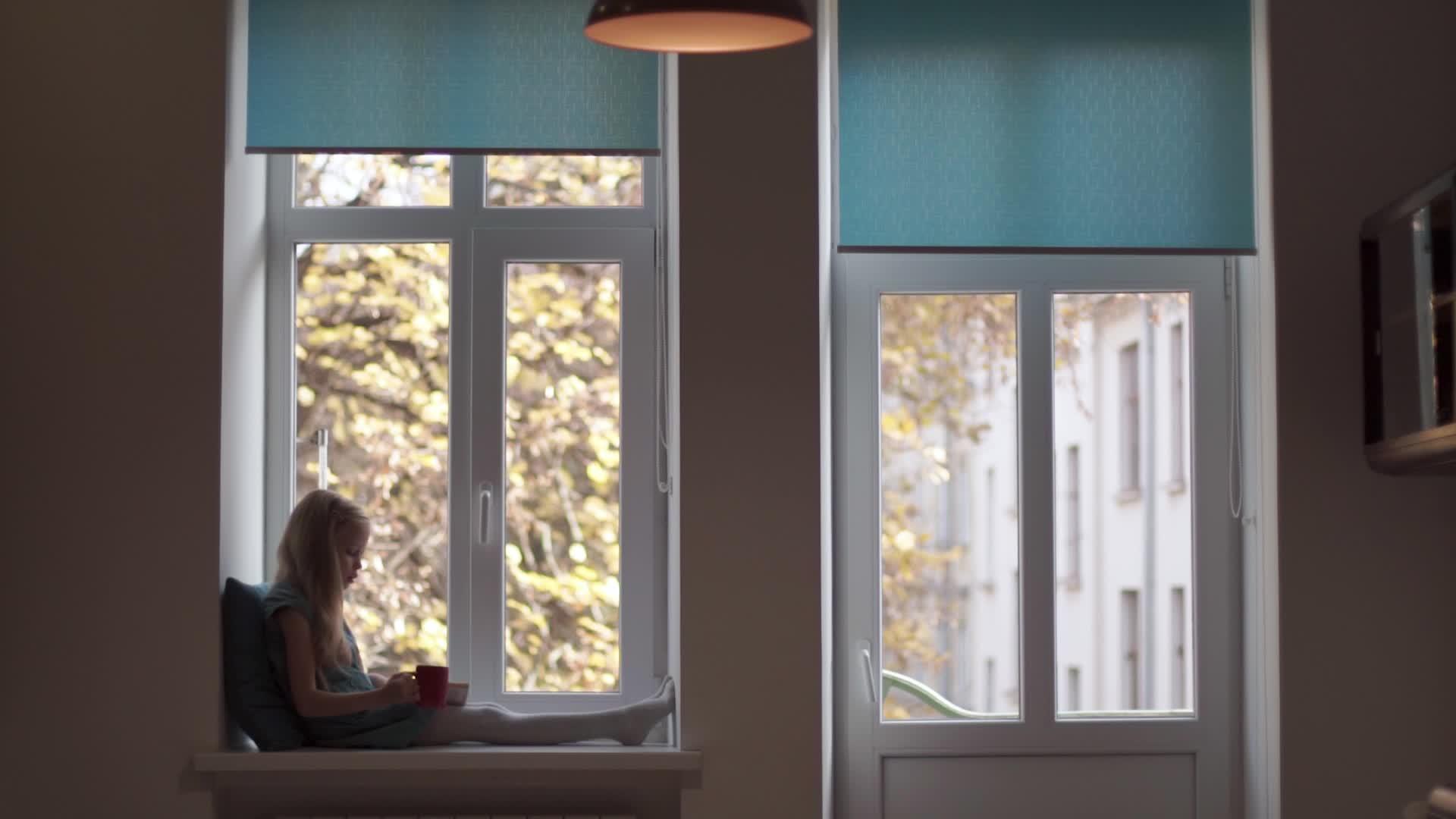 穿着绿色裙子的女孩在窗台上看书喝红杯子视频的预览图