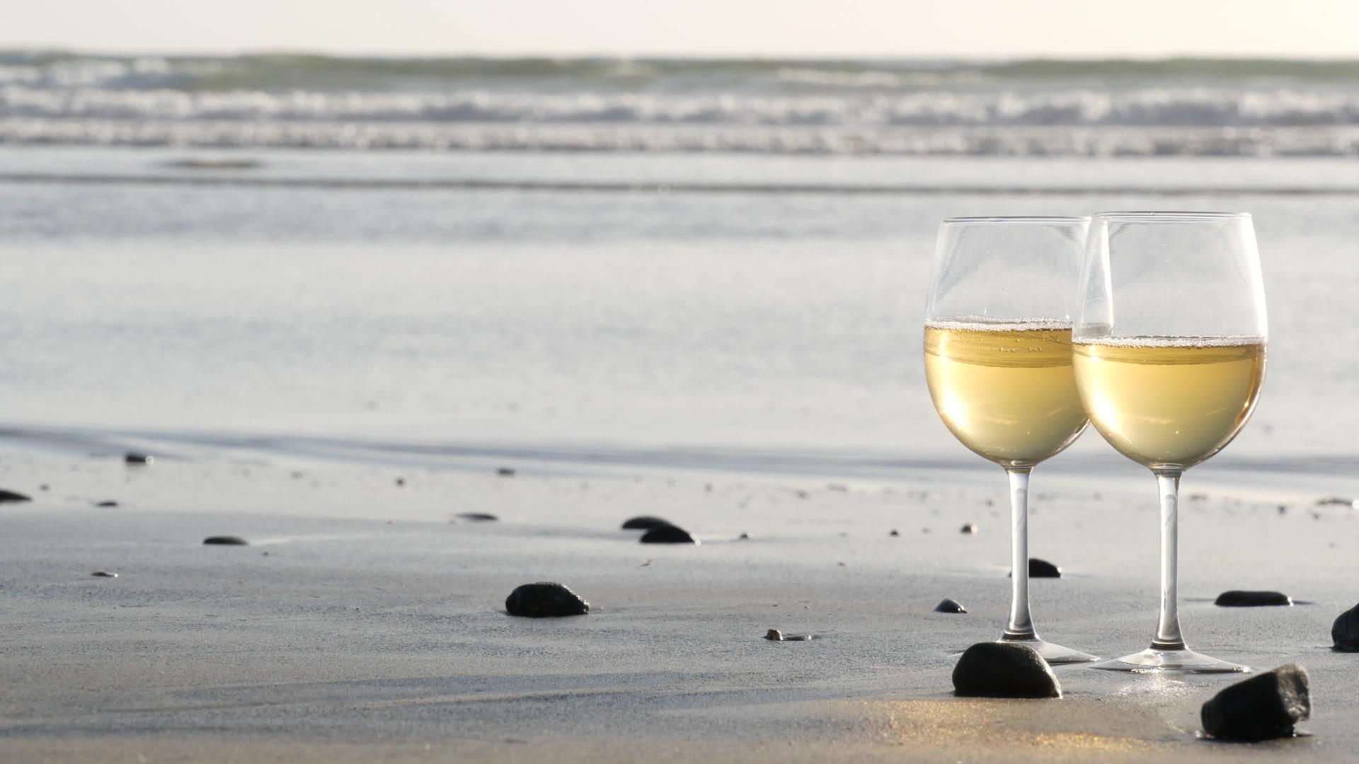 两杯红酒在海边一杯白葡萄酒浪漫约会海水日落波浪视频的预览图