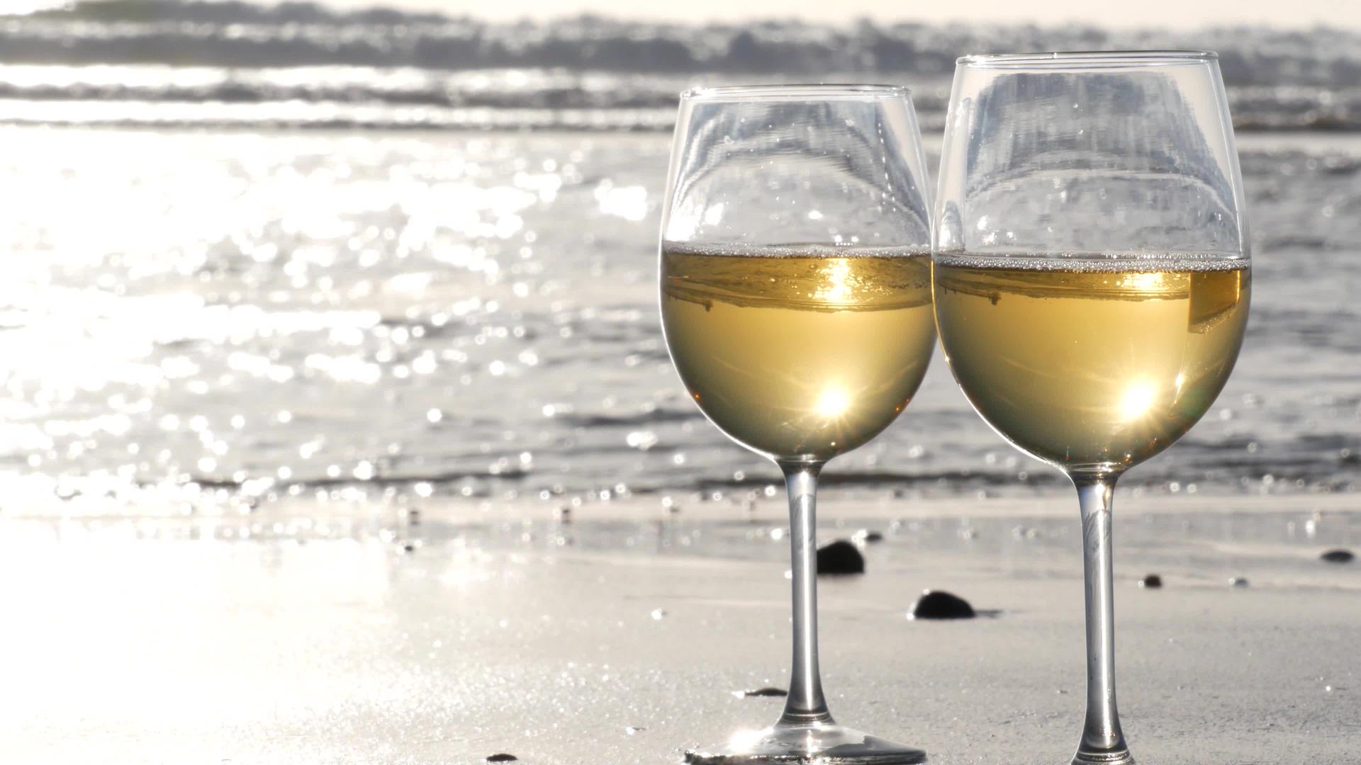 两杯红酒在海边一杯白葡萄酒浪漫约会海水日落波浪视频的预览图