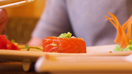 男人手里拿着寿司卷和筷子 在餐馆里倒酱油视频的预览图