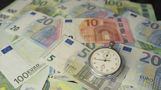 货币宏观拍摄手表位于钞票层的中心时钟时间是金钱视频的预览图
