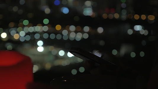晚上浏览智能手机的背景是城市灯光视频的预览图