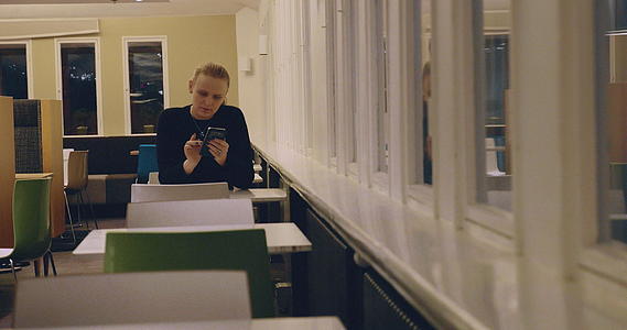 女人独自坐在咖啡馆里用手机过夜视频的预览图