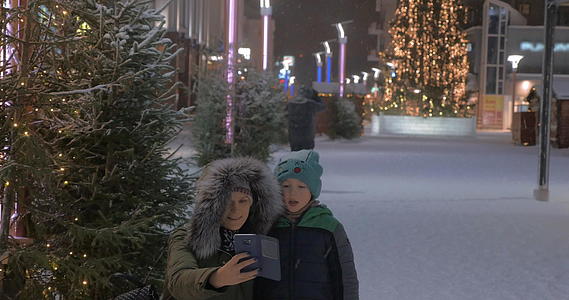 母亲和孩子在街上自拍冬衣和圣诞照片视频的预览图