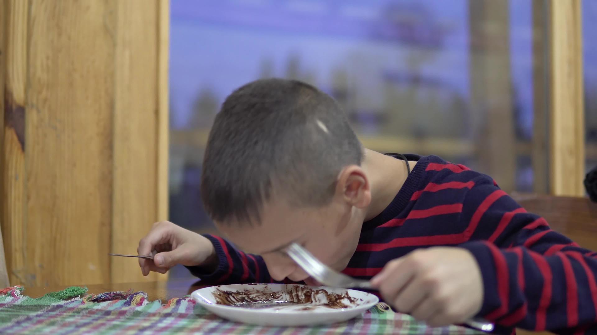 小男孩在餐馆里吃煎饼烤蛋糕做美味的蛋糕和糖霜视频的预览图
