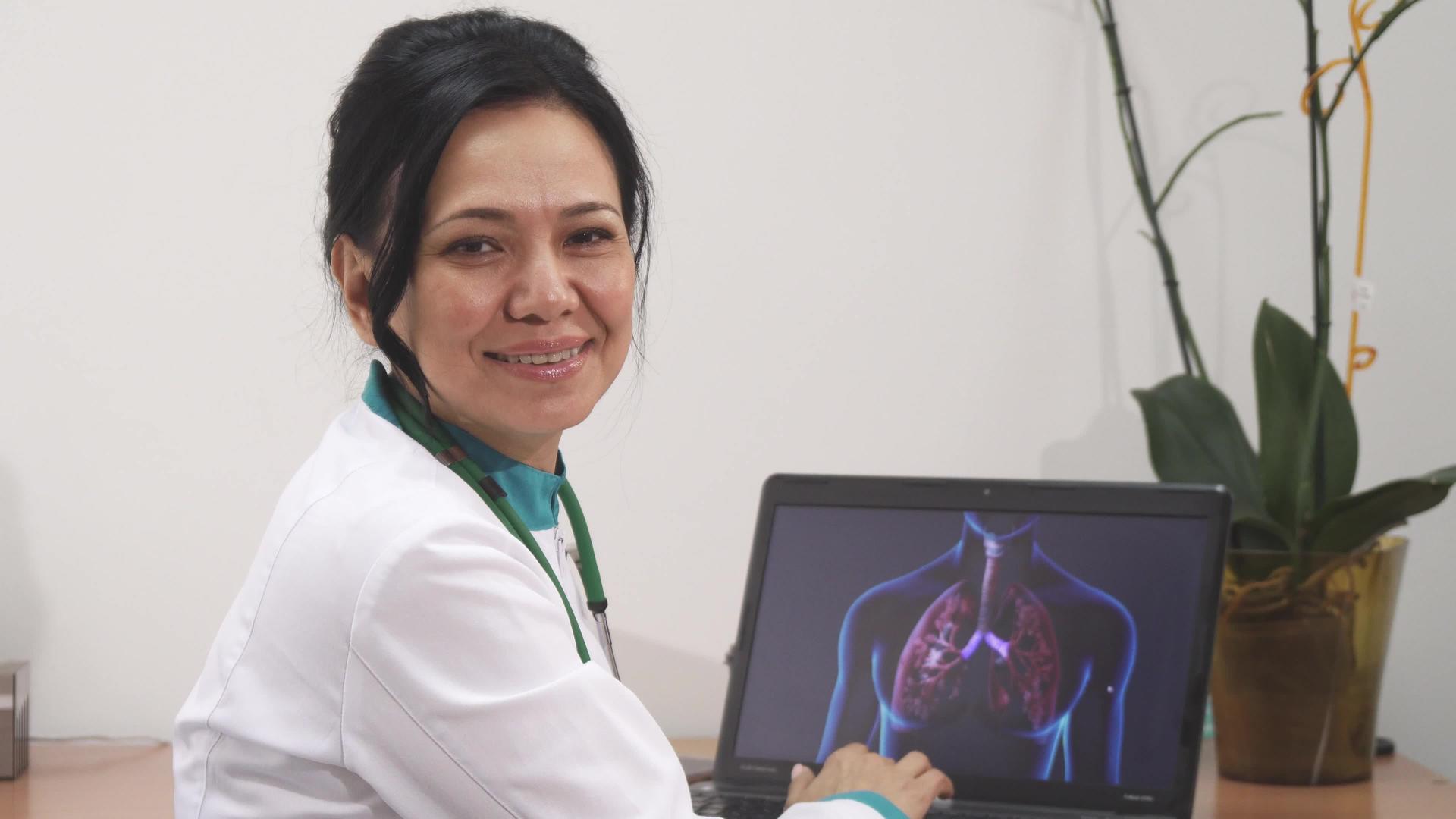 一位成熟的女医生在诊所检查了膝盖上的便携式电脑肺部扫描视频的预览图