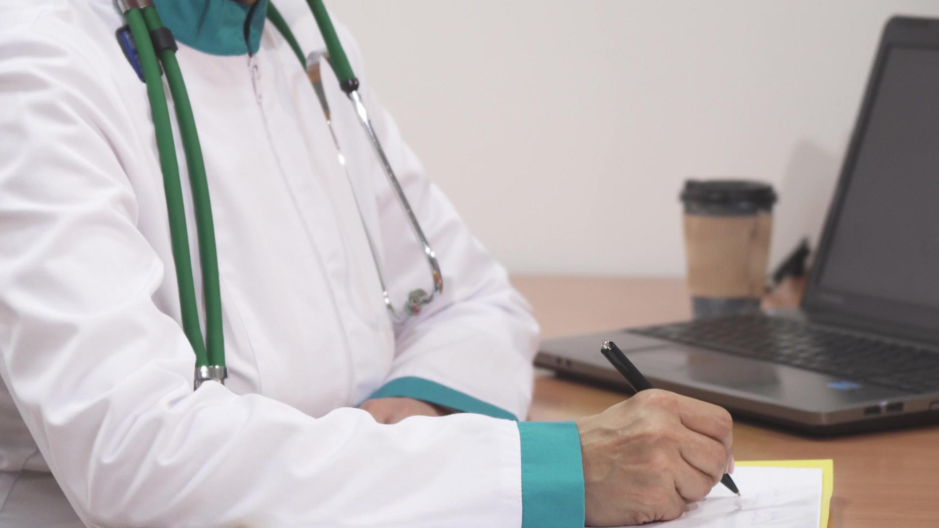 一名女医生在工作时微笑着填写医疗文件并闭嘴视频的预览图