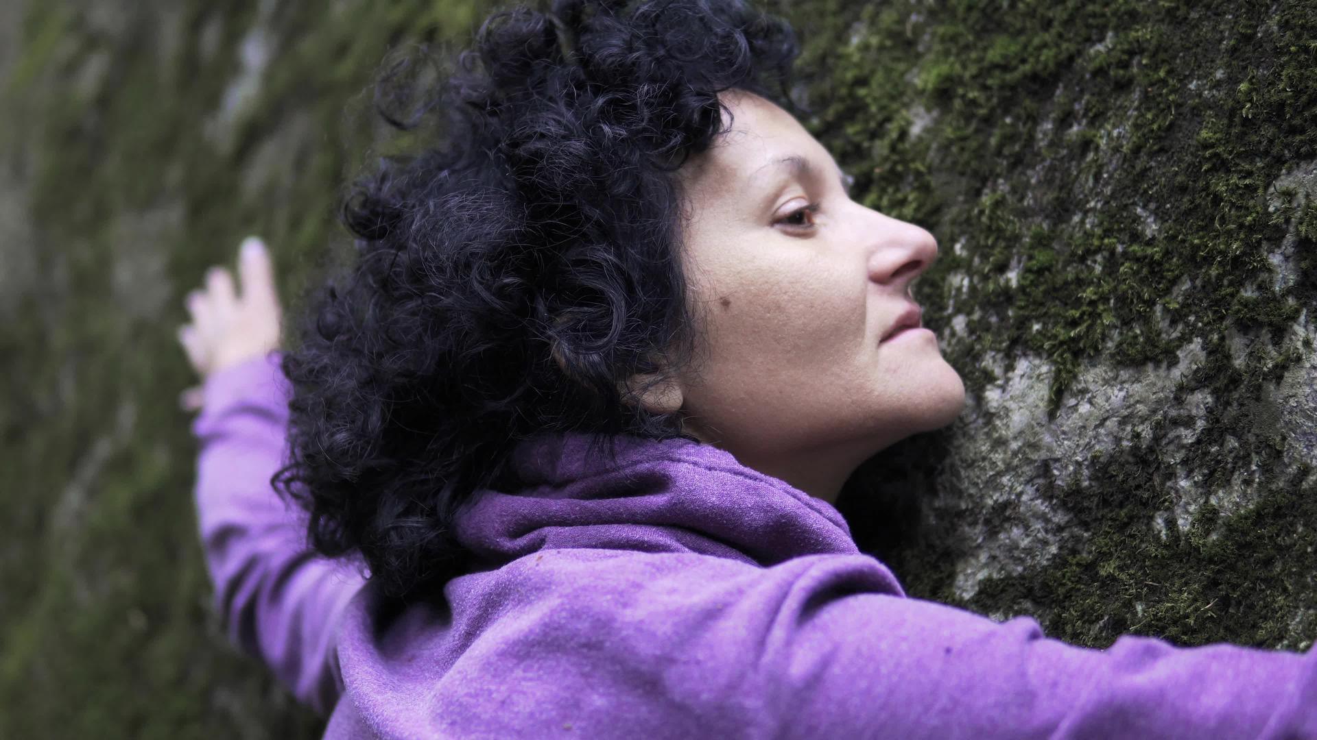 女人用莫斯的手臂在大石头上交换情感和自然能量视频的预览图