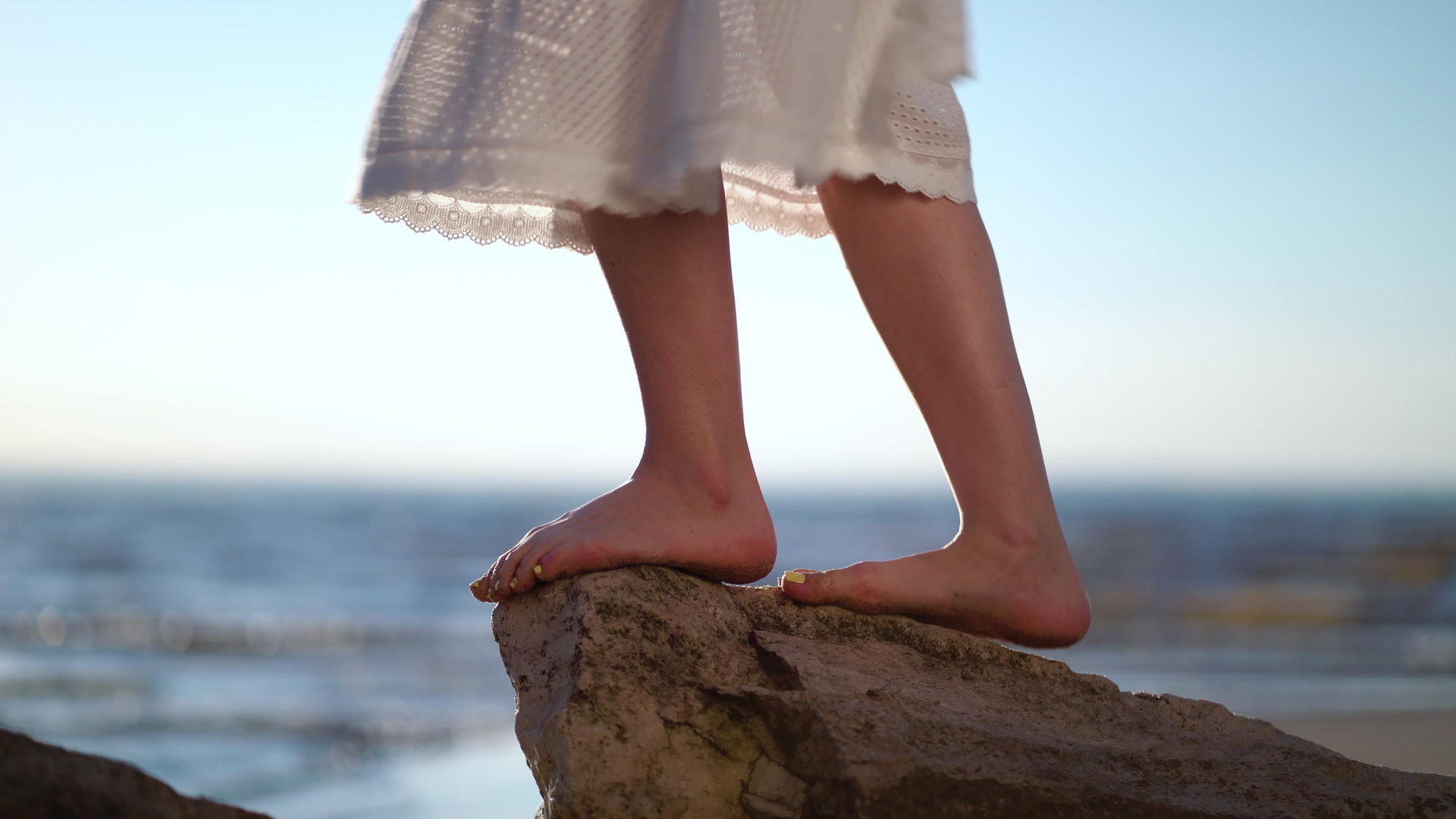 女人的脚站在长凳上的一块石头上海石头海滩上的女人视频的预览图