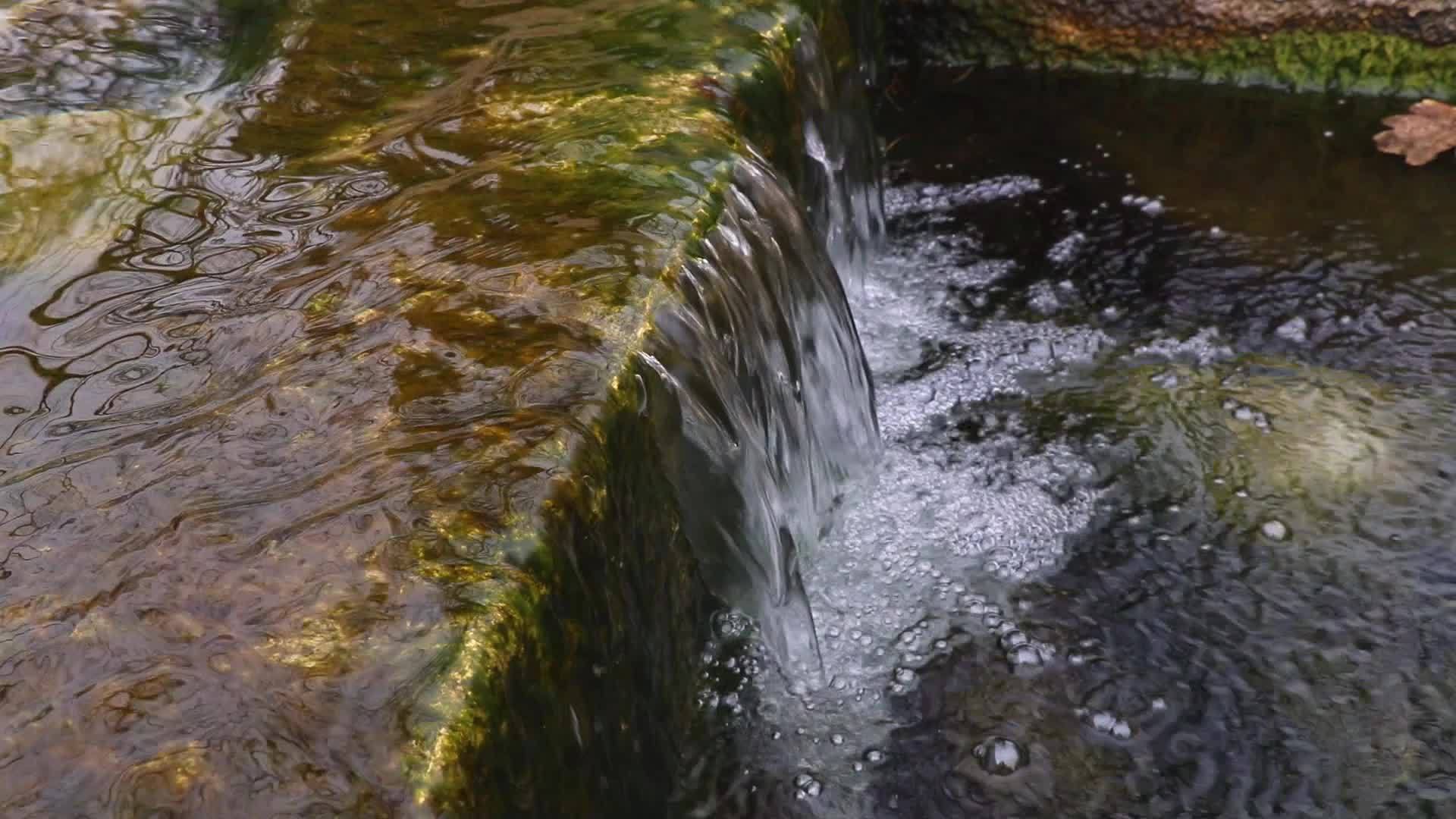 冰冷透明的水流过石头和木板视频的预览图