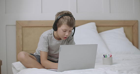 小男孩在网上用笔记本电脑和家里的笔记本电脑Wifi网络绘画视频的预览图