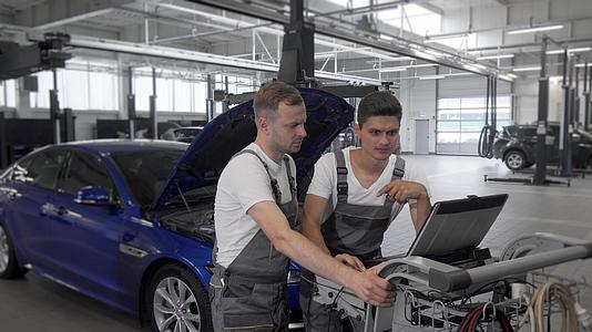 成熟的机械师和助手车维修站在汽车修理站使用计算机视频的预览图
