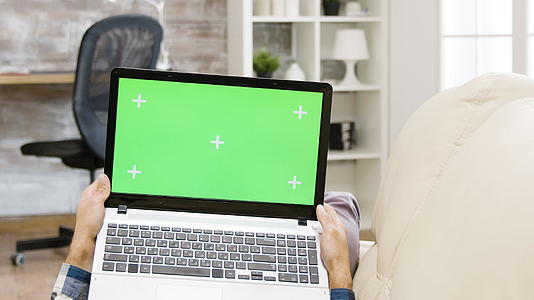 对持有绿色屏幕笔记本电脑的人的准光片进行放大视频的预览图