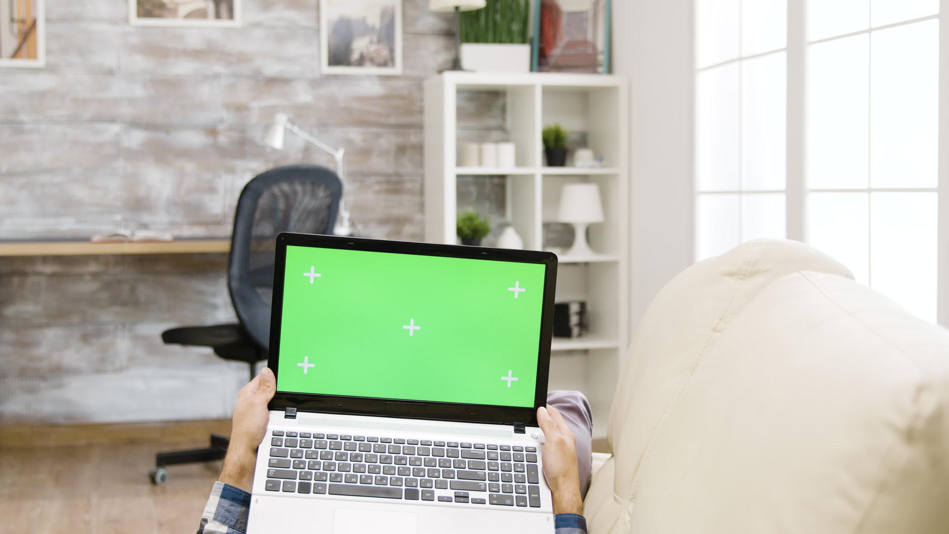 一名男子躺在沙发上拿着一台绿色屏幕笔记本电脑视频的预览图