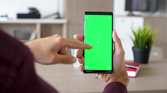 男人的手在智能手机上滚动用绿色屏幕染色体模拟视频的预览图