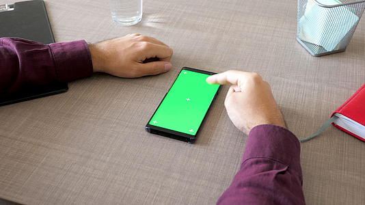 智能智能手机由绿色屏幕染色系统制成模拟桌上的男性手视频的预览图