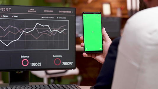 Caucasian商人用绿色屏幕看手机视频的预览图
