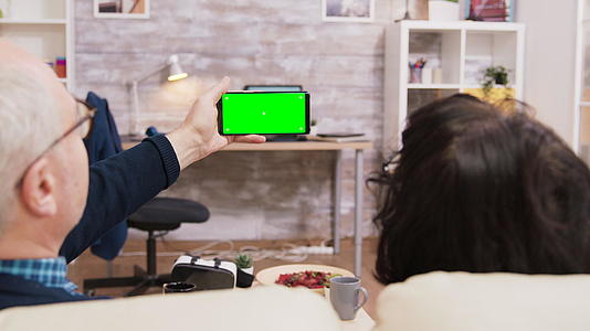 在绿屏上看电话的老夫妇背面的颜色视频的预览图
