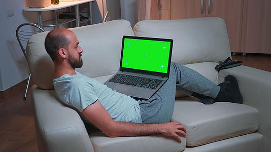 坐在沙发上用笔记本电脑浏览营销信息的人视频的预览图