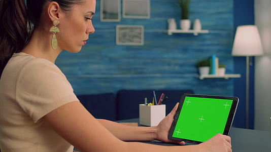 使用绿色屏幕平板电脑模拟在办公桌上工作的女性员工视频的预览图