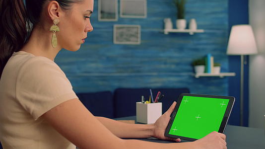 自由自由职业者使用平板电脑和模拟绿色屏幕显示器阅读在线书籍视频的预览图