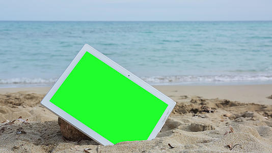 海滩上有绿色屏幕的平板电脑视频的预览图
