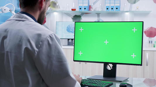 医生在绿屏电脑上打字的缩放镜头视频的预览图