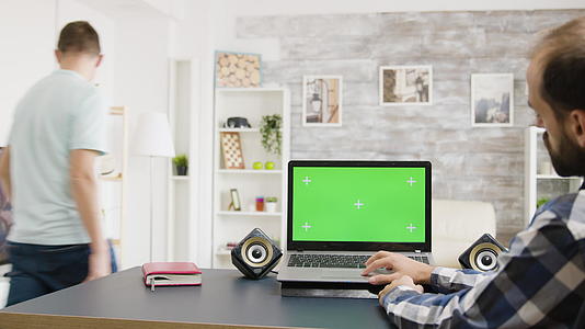男人在绿色屏幕笔记本电脑上用明亮非常明亮的方式浏览互联网视频的预览图