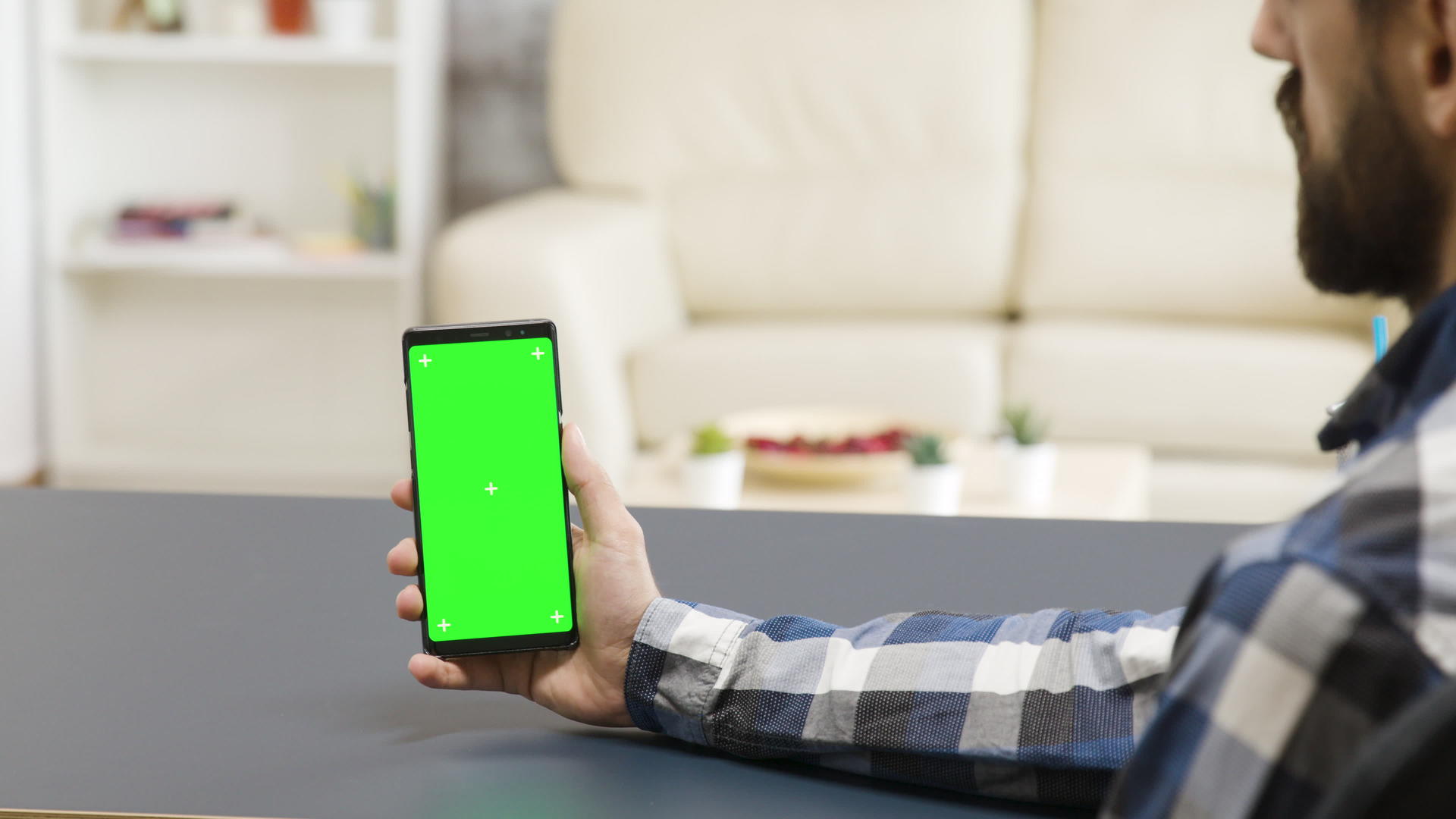 在现代和明亮的生活空间中男人有绿色屏幕的手机视频的预览图