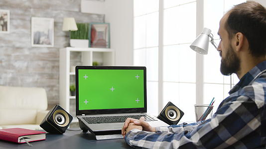 用绿色屏幕看笔记本电脑的人的镜头放大肩膀视频的预览图