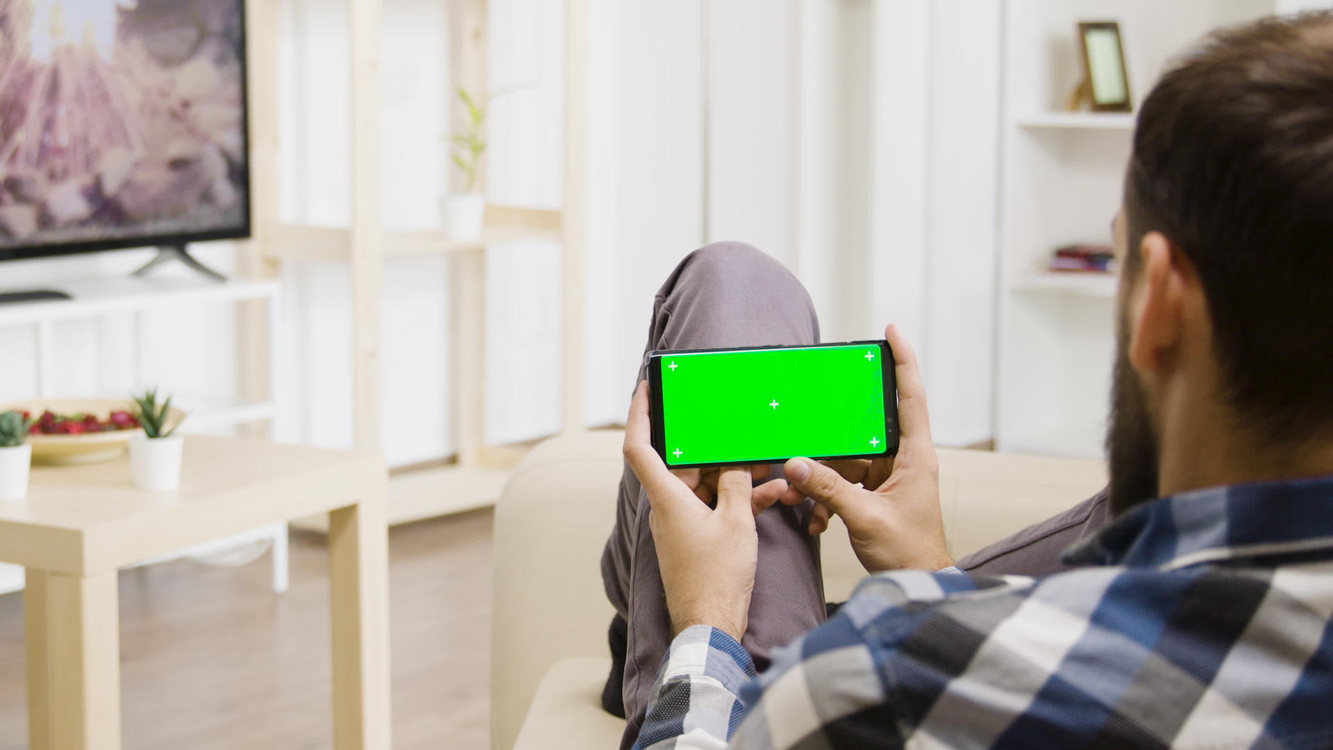 这名男子手里拿着一部绿屏智能手机看电视视频的预览图