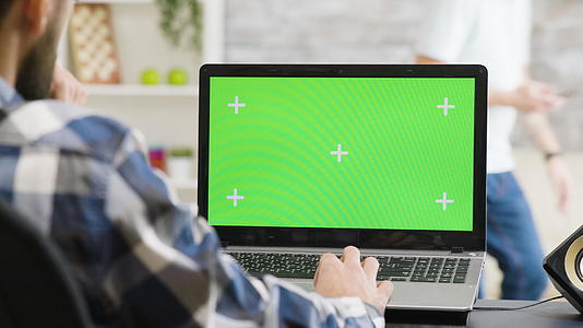 笔记本电脑在一个非常明亮的生活空间里用绿色屏幕工作视频的预览图