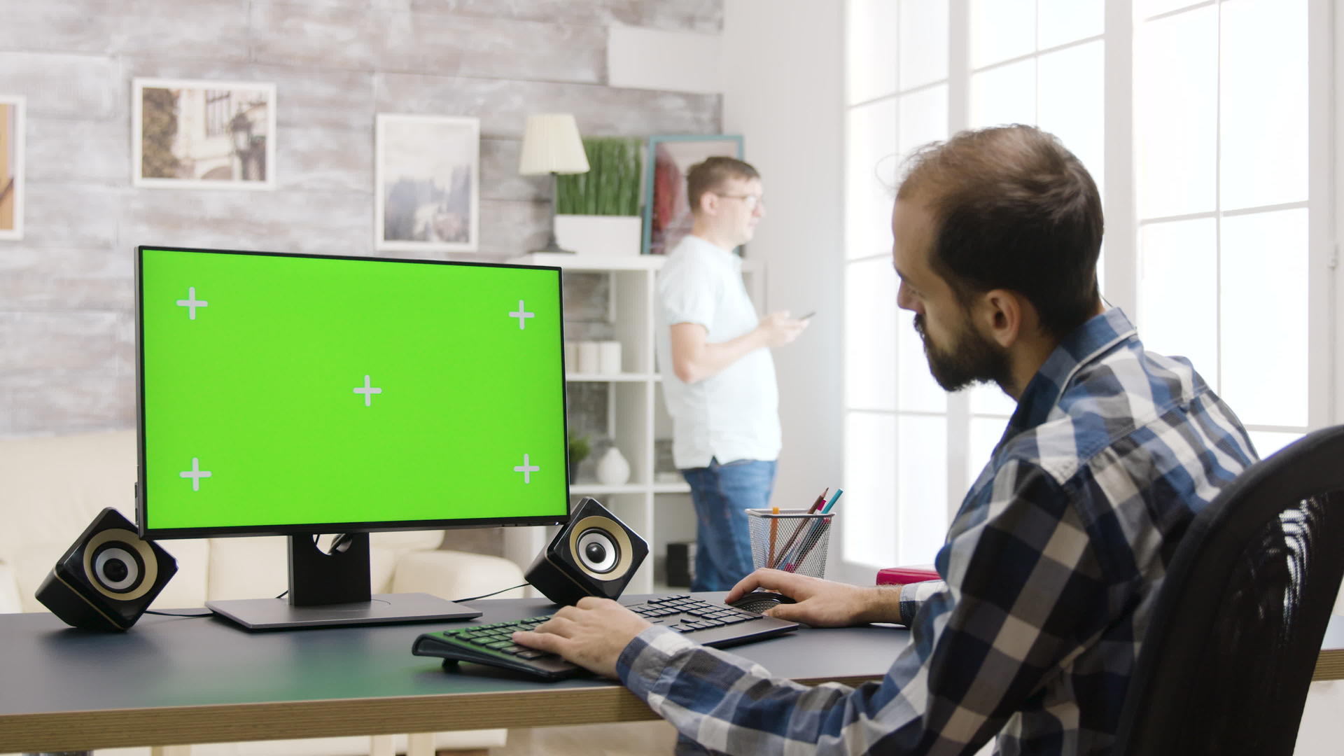 在明亮明亮的客厅里使用绿色屏幕Pc年轻人工作视频的预览图