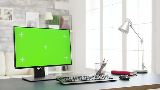 在明亮的客厅中使用孤立的绿色屏幕监视器Pc视频的预览图