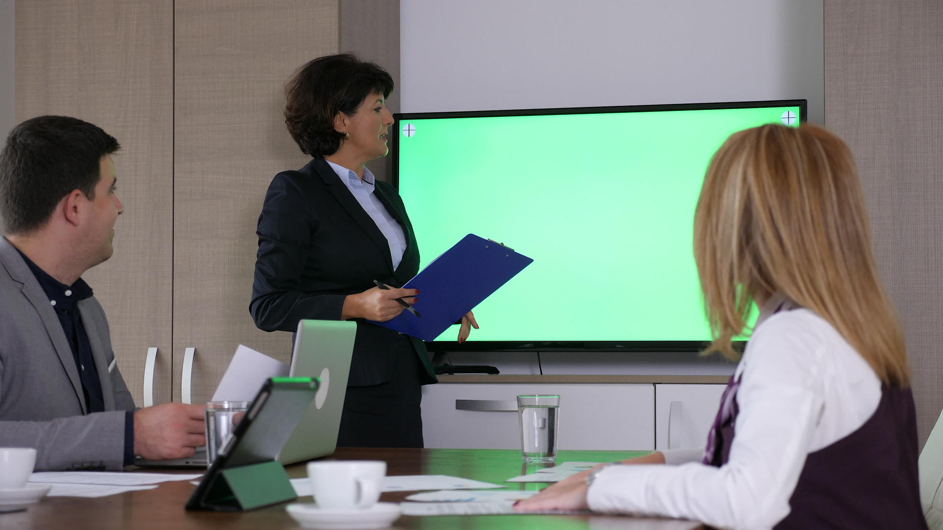商业女商人在绿色屏幕上tv上展示视频的预览图