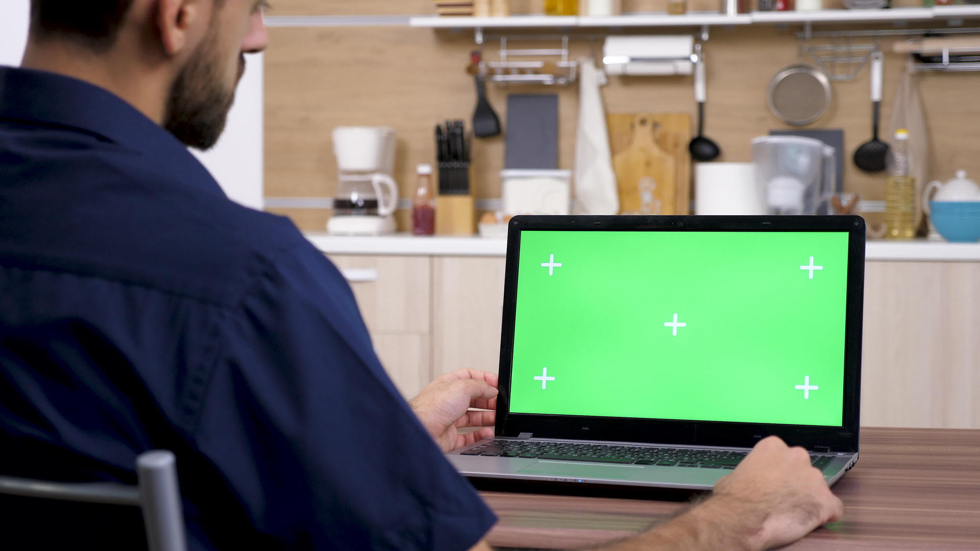 厨房里的男人正在用绿色的屏幕看电脑视频的预览图