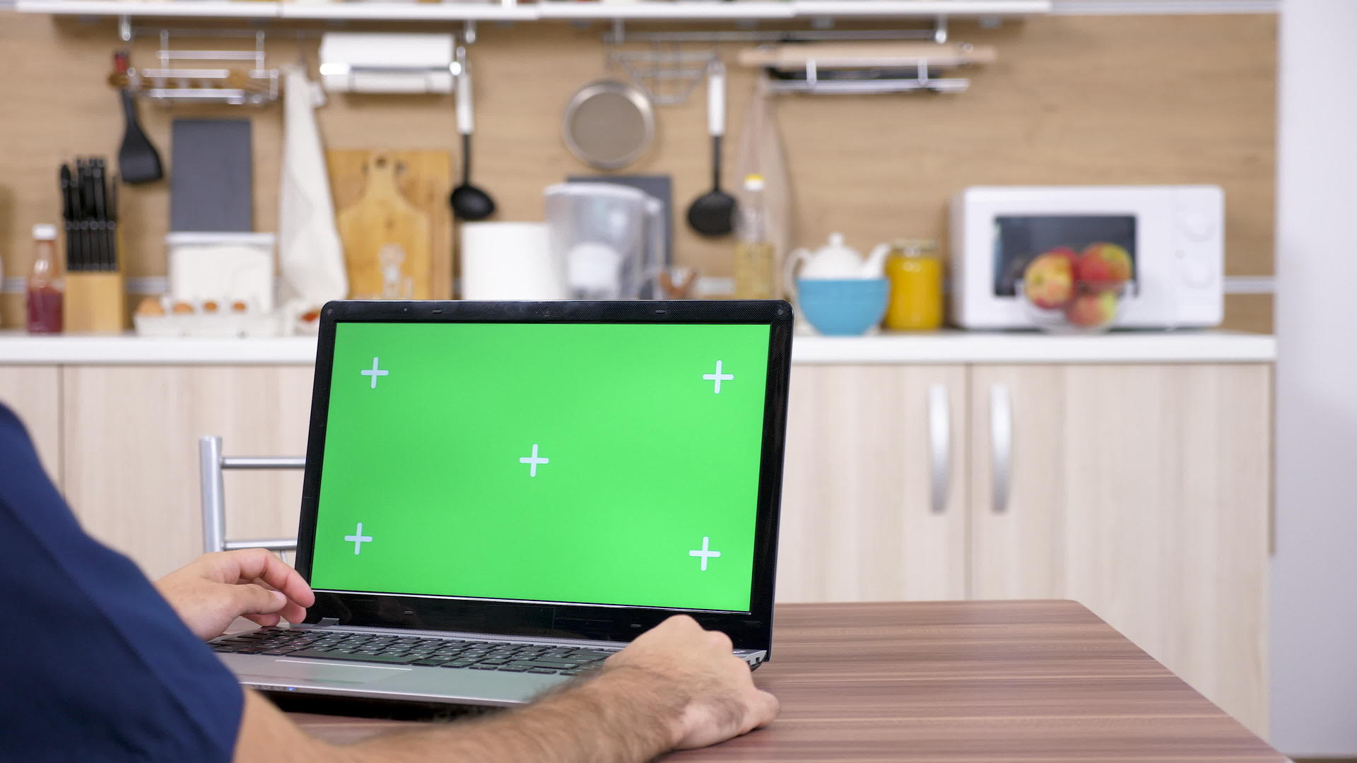 厨房里的男人正在用绿色屏幕看笔记本电脑视频的预览图