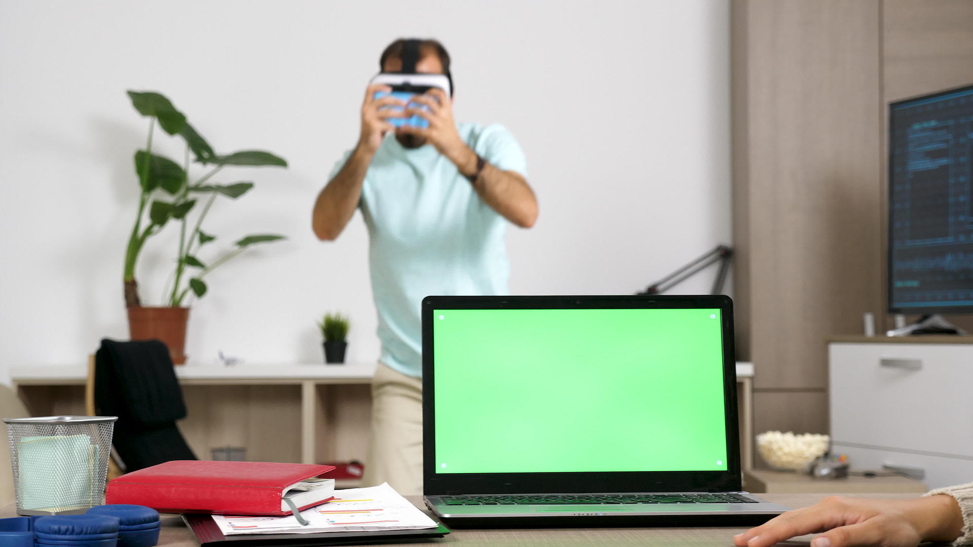 男人玩虚拟现实视频游戏而办公桌上的女人一边打电话一边打电话视频的预览图