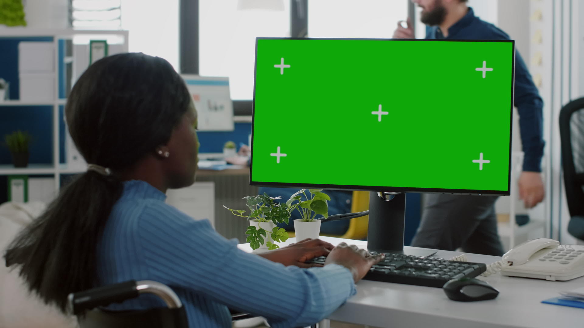 坐在轮椅上的黑黑女商人使用绿色屏幕Pc视频的预览图
