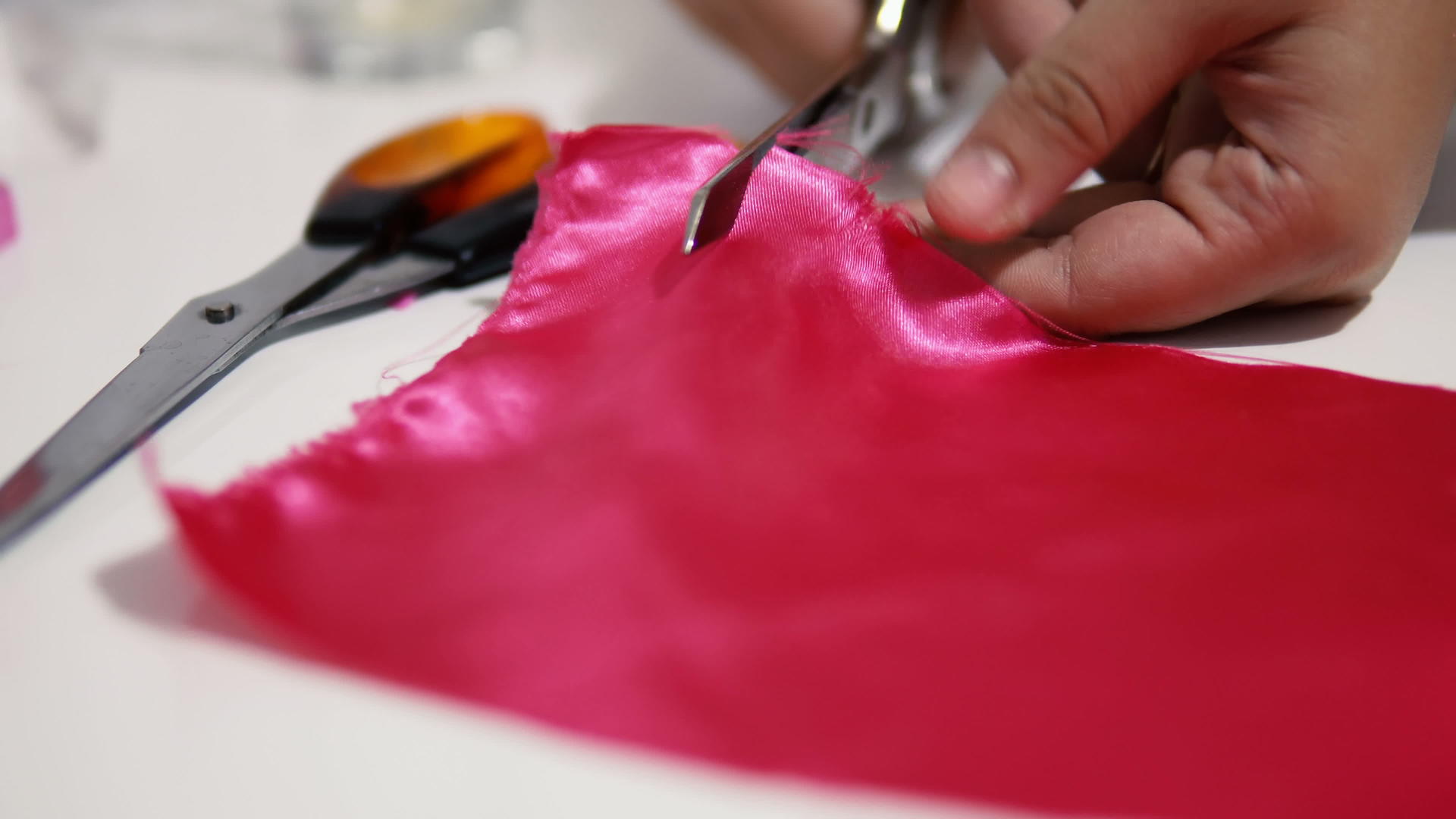 纺织业用剪刀切割粉色织物视频的预览图