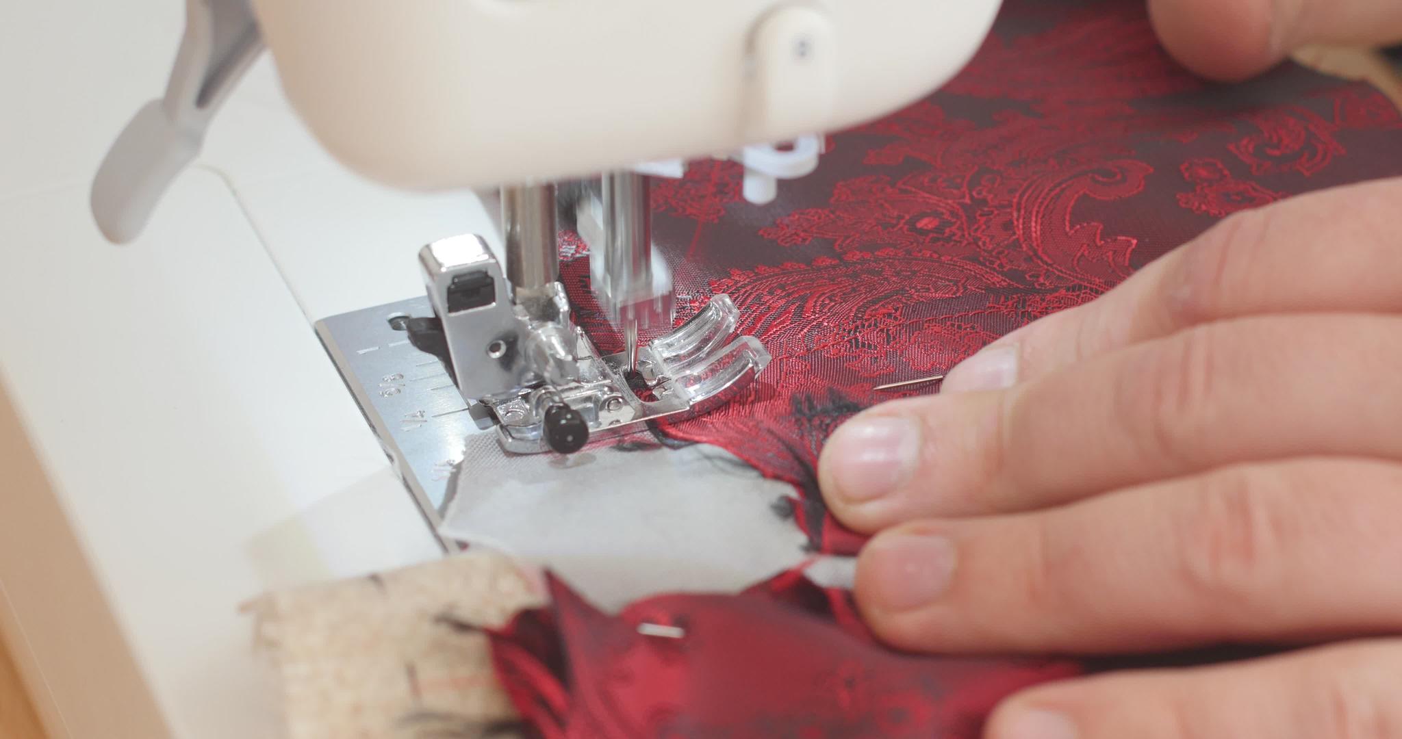 在制作西装的过程中英俊的男手通过缝纫机推动红色的佩斯利视频的预览图