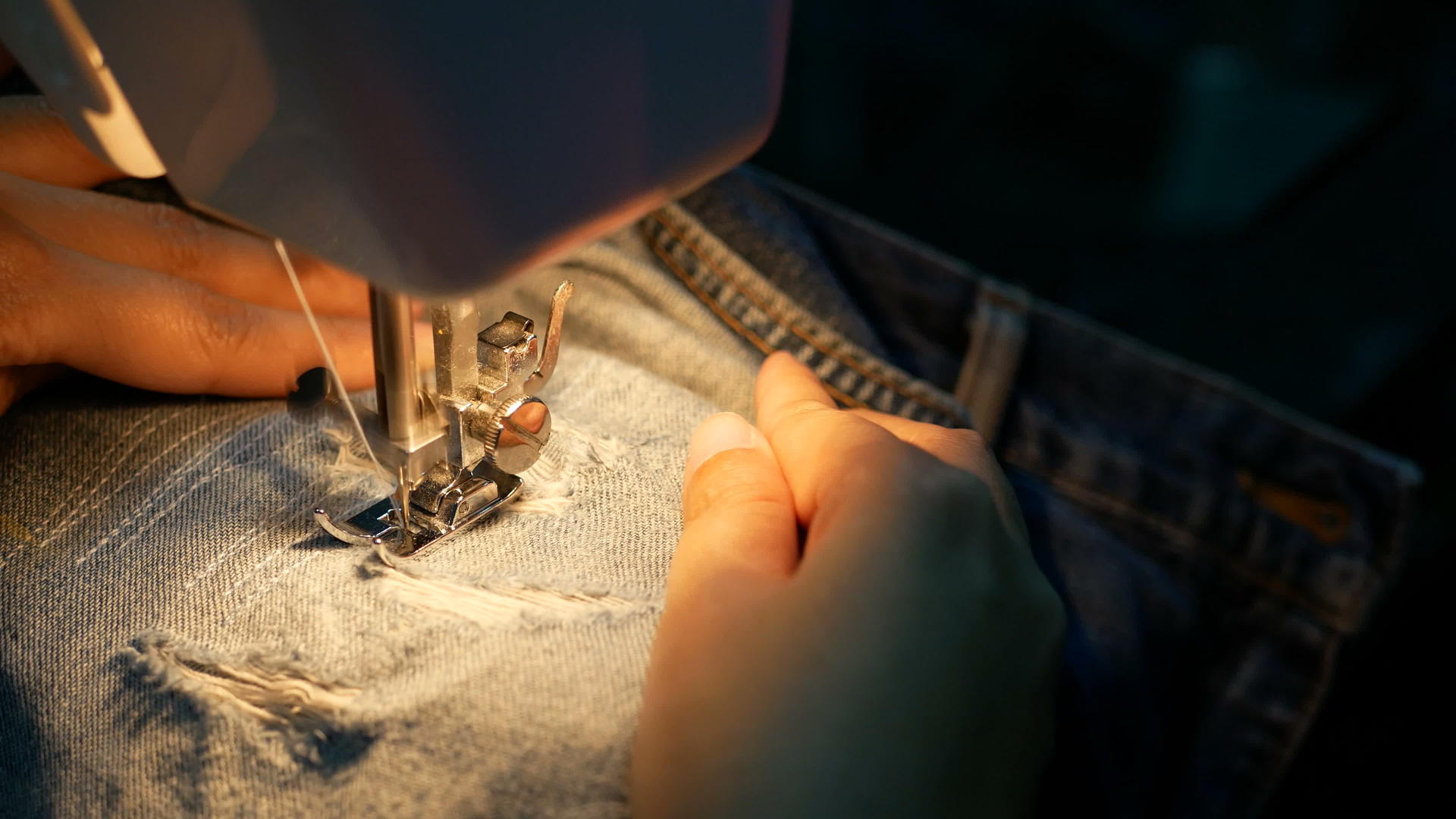 关闭一名女子用缝纫机修理蓝色牛仔裤和缝纫机视频的预览图