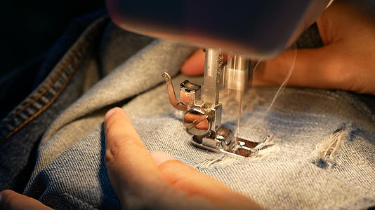 4k关闭一名女子用缝纫机修理蓝色牛仔裤视频的预览图