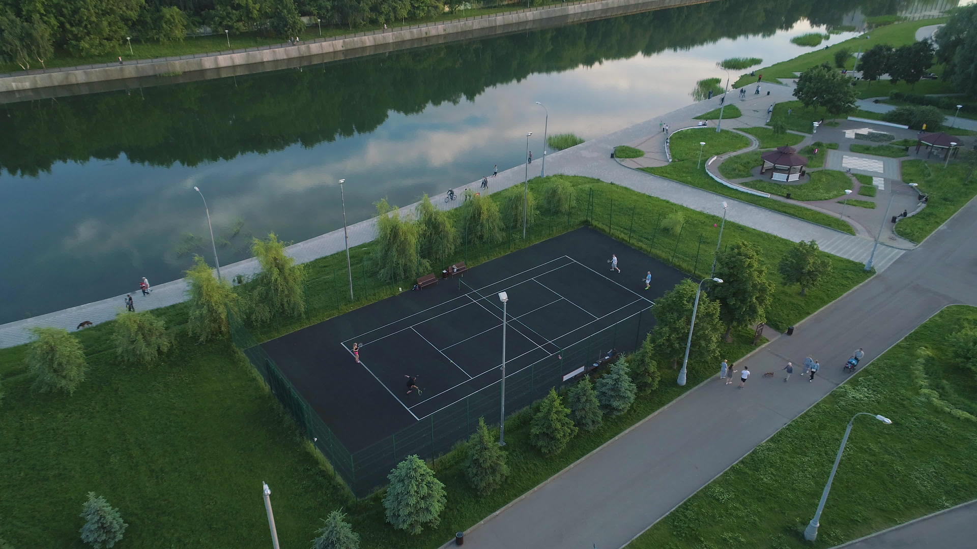 在绿色城市公园的球场上打网的球员们在人行道上行走视频的预览图