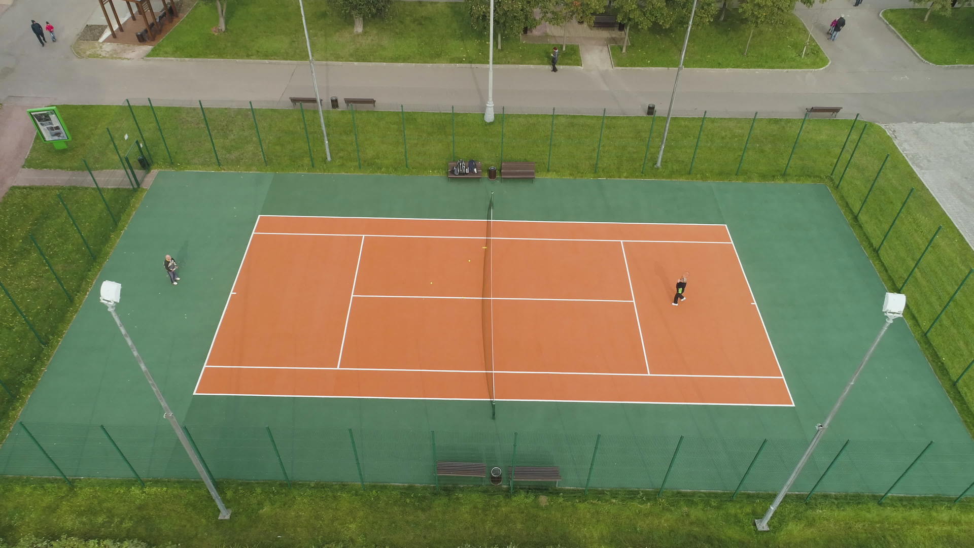 成年人在绿色公园的球场上打网球空中摄像头向下倾斜视频的预览图