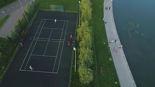 在绿色城市公园的一个体育场里打网球的球员飞回空中最高的空中视频的预览图