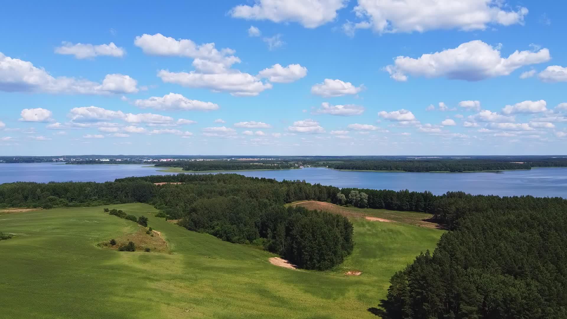 无人机从绿草中起飞观察蓝湖和白云的场景视频的预览图